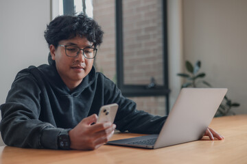businessman using a smartphone while sitting at a desk with a laptop in a modern office environment.using artificial intelligence smart apps