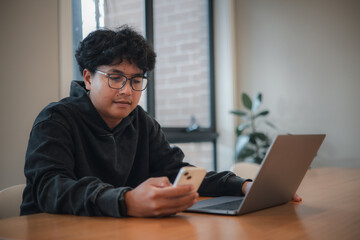 businessman using a smartphone while sitting at a desk with a laptop in a modern office environment.using artificial intelligence smart apps