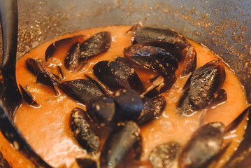 mussels fried in broth in large frying pan outdoors, delicious food