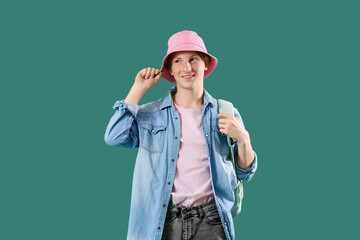 Male student in bucket hat with backpack on green background