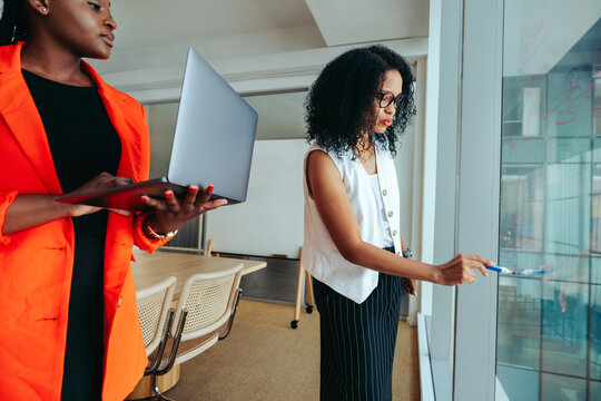 Collaborative design planning in modern agency with professionals using glass whiteboard for brainstorming
