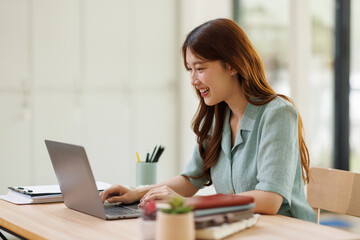 Young business woman using calculator and laptop for doing math finance on an office desk, tax, report, accounting, statistics, and analytical research concept
