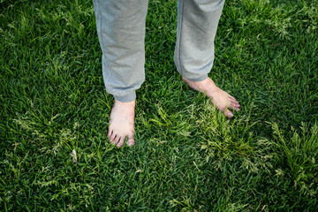 A person enjoys the sensation of soft grass underfoot in a serene outdoor setting, enhancing their...