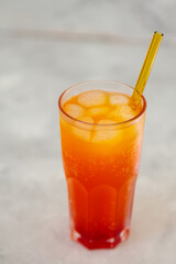 Refreshing Orange Carbonated Drink with Ice Cubes in Tall Glass on Gray Surface, Trendy Dirty Soda Concept