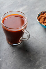 Cocoa Drink in Transparent Cup and Cocoa Powder in Bowl on Gray Concrete Background