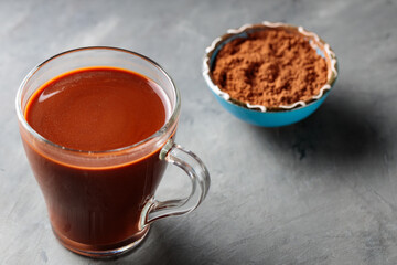 Cocoa Drink in Transparent Cup and Cocoa Powder in Bowl on Gray Concrete Background
