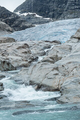 vertical shot Norwegian mountain glacier with meltwater gushing in the foreground