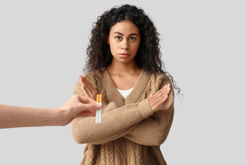 Young African-American woman rejecting cigarettes on grey background. Stop smoking concept