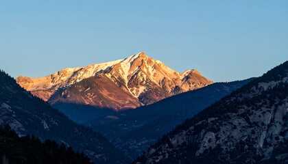 Mountain peak illuminated by sunrise while the valley remains in shadow.