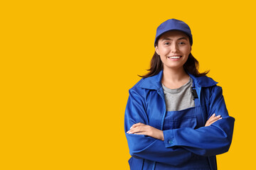 Young female mechanic on yellow background. Woman in male profession concept