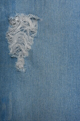 Ripped blue hipster jeans material. Destroyed denim Cloth texture. Close up.