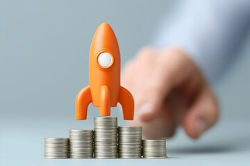 Orange rocket on stacks of coins symbolizes financial growth, investment, or startup success with a hand ready to launch.