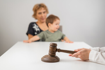 A judge hits a gavel against the backdrop of an elderly woman holding a child. 