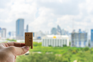 House model in home insurance broker agent’s hand with building background. Real estate agent...