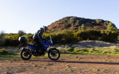 Obraz premium Driver riding motorcycle on empty asphalt road, spring mountains