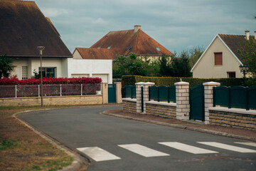 Quiet suburban street with crosswalk and detached houses on overcast day