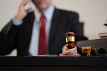 Justice and law concept.Male judge in a courtroom the gavel, working with digital tablet computer on wood table.