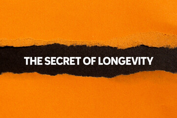 The secret of longevity message written on ripped torn orange paper on black background. Conceptual...