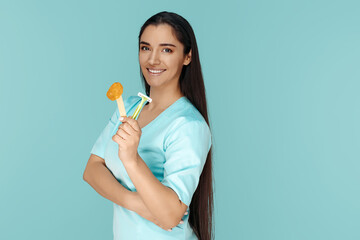 Cosmetologist holding sugaring paste and razor for depilation procedure over blue background