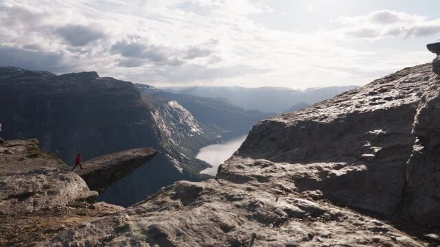 Person standing on cliff edge, dramatic Norway fjord view, sense of freedom and awe, Trolltunga