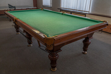 Billiard table with green baize. Billiard room. Board game. Billiard club for relaxing in your free time. Billiard table lighting.