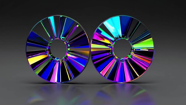 Two colorful glass discs are rotating, showing a circular pattern with vibrant hues, placed on a reflective surface that mirrors their intricate design, creating a mesmerizing visual effect