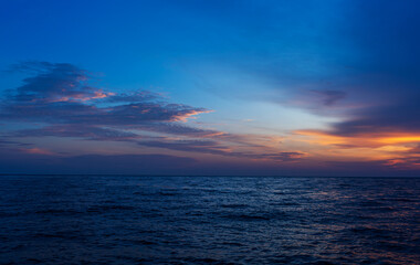 Obraz premium Colorful sunset over the sea with dramatic clouds and a peaceful ocean horizon.