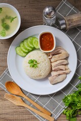 Chicken and rice with coriander and cucumber with sauce and soup in a white plate, hainanese chicken rice, thai called khao man gai, asian food, thai food