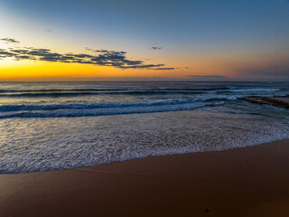 Sunrise at the beach with waves and a smattering of clouds