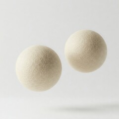 Floating pair of wool dryer balls in cream color on a solid white background