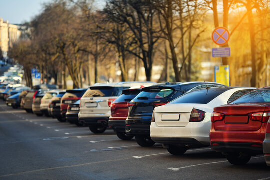 Cars parked in angled row formation in crowded city parking lot. Downtown parking situation with tightly parked cars in an angled layout, limited city infrastructure and high urban vehicle density