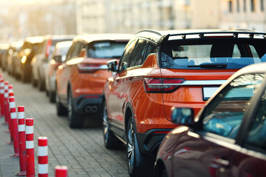 Parked cars in a city parking lot with bright orange traffic cones marking separation from the sidewalk to ensure safety and regulate pedestrian and vehicle flow..