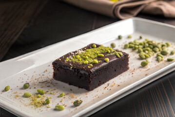 A tempting chocolate dessert, garnished with crushed pistachios, delightful gourmet dining. Brownie cake with restaurant serving