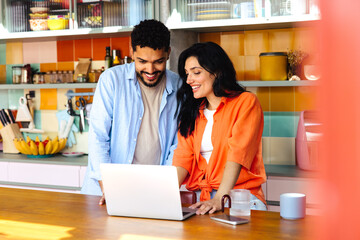 Couple using a laptop together in a modern kitchen setting