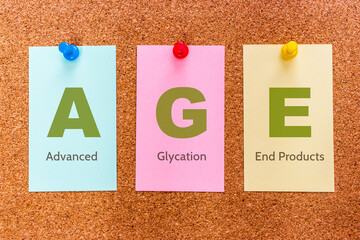Conceptual 3 letters keyword AGE (Advanced Glycation End Products), on multicolored stickers attached to a cork board.