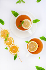 Fresh lemon slices on skewers and a cup of tea with mint and lemon, styled as a clean background image.