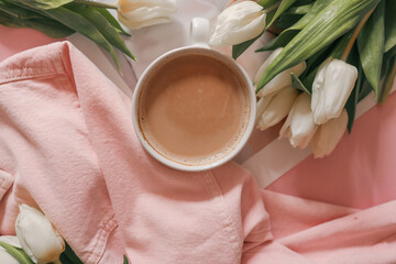 Flat lay with white tulips in a soft pink denim jacket, a fashion magazine, and a cup of coffee on...