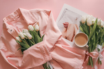 Flat lay with white tulips in a soft pink denim jacket, a fashion magazine, and a cup of coffee on...