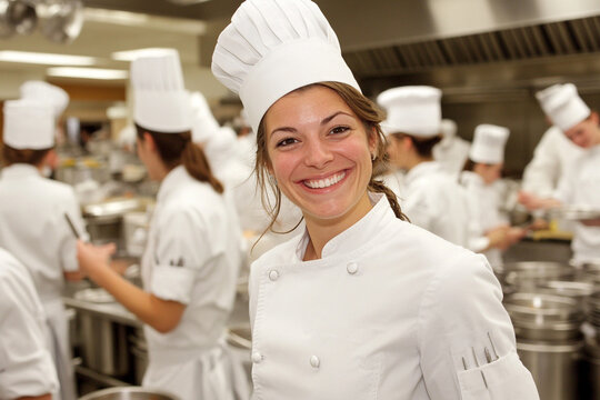 Chef students actively engaged in culinary practice at a professional cooking school in a busy kitchen environment