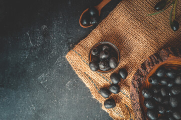 Top view of rustic composition with black olives in a wooden bowl, a wooden spoon, a glass bottle...