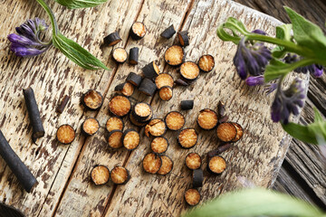 Cut up comfrey or Symphytum root on a wooden board - ingredient for herbal tincture