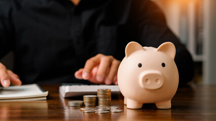 Concepts of saving money and financial planning. Man hand holding piggy bank on wood table, income, return, retirement, compensation fund, investment, dividend tax, stock market