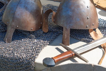 Medieval armor set with helmets and sword on chainmail display