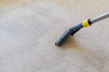 Carpet cleaning process with vacuum cleaner on beige rug