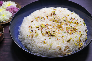 Closeup of Sutarfeni, a traditional Indian sweet made from fine sev soaked in sweet saffron flavored milk, garnished with dry fruits. Perfect for festive celebrations and Indian cuisine themes. copy