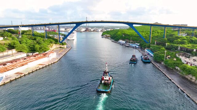 Tugboats sailed on Sint Anna Bay with Koningin Julianabrug bridge in Willemstad historic city center, Curacao. Historic Willemstad is a UNESCO World Heritage Site. 