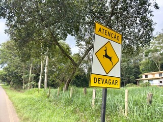 Placa de sinalização de pedestre e animais na pista e ciclista devagar.