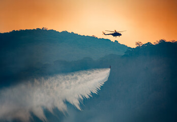 Fire fighting helicopter dropping water to put out a forest fire.
