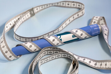 Ozempic syringe pen and measuring tape on blue