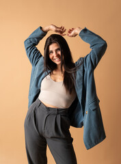 Young stylish woman dancing and smiling with arms raised